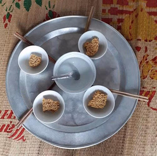Khá khẩm hơn thì mâm cơm này có mì và một bát nước lọc ở giữa.