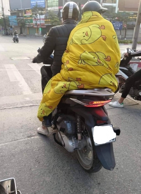 Nhân ngày thời tiết không được đẹp cho lắm, khi bên ngoài trời đã mưa còn trở lạnh nhưng vẫn phải đi làm sớm, thay vì mặc thêm tấm áo để giữ ấm, nhiều người lại khoác lên mình tấm chăn mỏng và cứ thế đi làm.