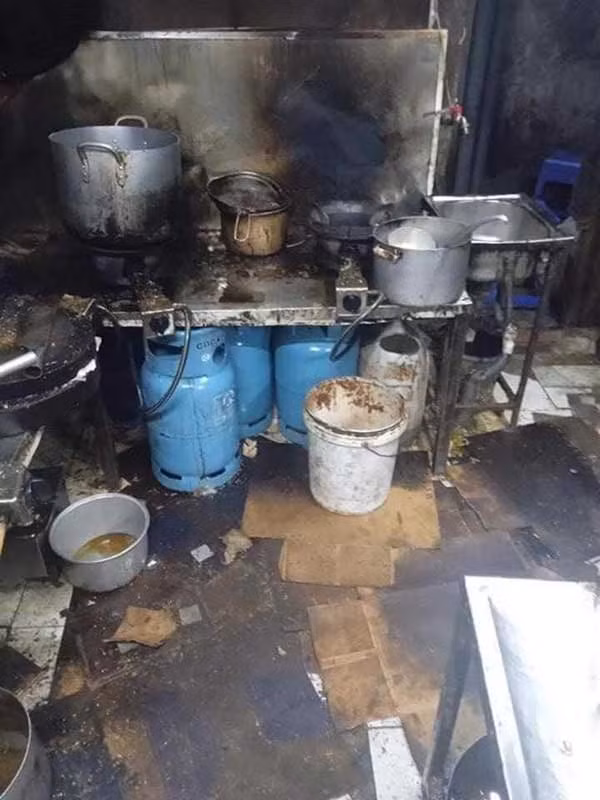 Thông qua hình ảnh có thể thấy, căn bếp đen kịt, nồi niêu xoong chảo nấu xong không được dọn dẹp lại vẫn vương đồ ăn rơi vãi, sàn được trải bằng những miếng lót bìa cũng đen bẩn không kém.