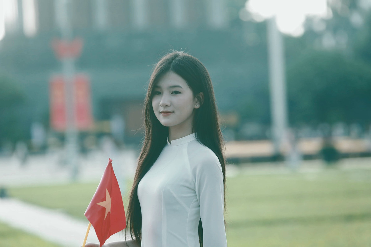 Thiếu nữ xúng xính trong bộ áo dài cùng cờ đỏ sao vàng chụp ảnh trước Quảng trường Ba Đình.
