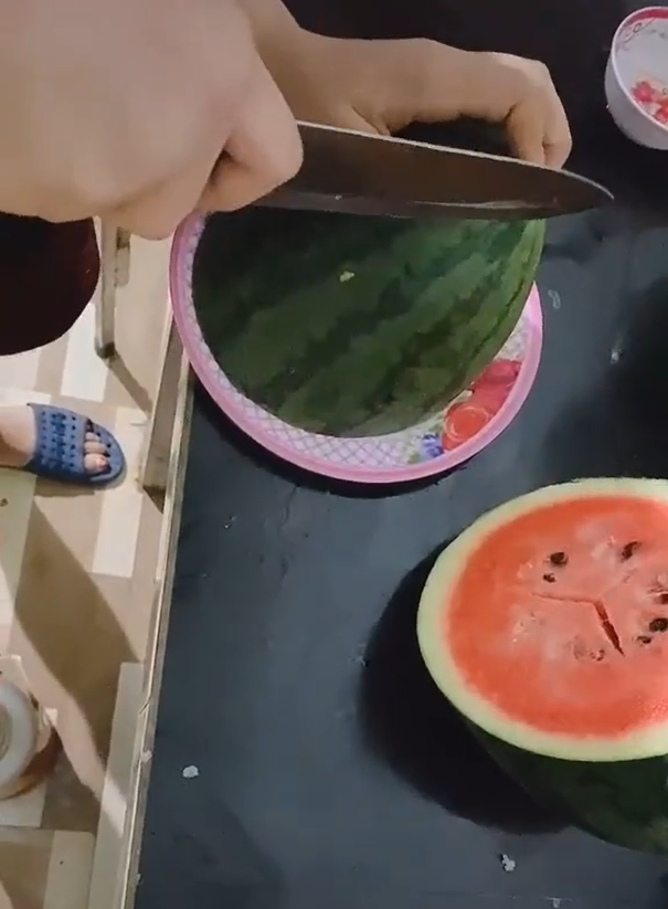 Cụ thể, trong đoạn clip được đăng tải trên TikTok, cô gái thay vì bổ quả dưa hấu chia đôi như thường thì lại đưa dao theo hương hơi chéo. Sau đó, cô chia một nửa quả dưa thành 4 lát và bỏ 2 lát ngoài cùng.