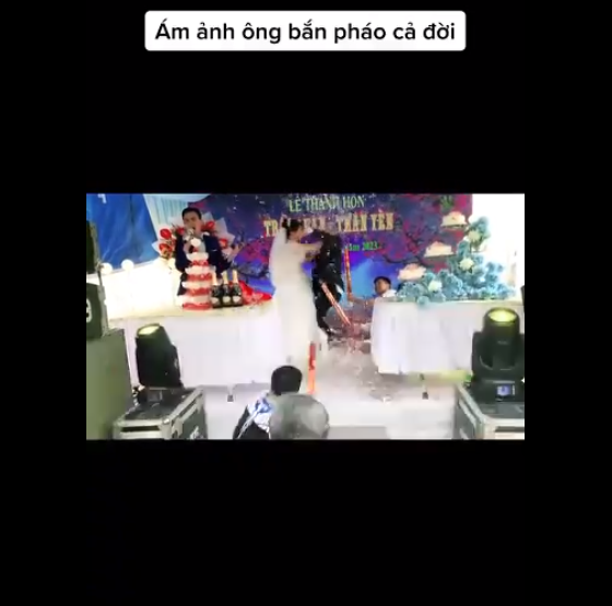 Theo đoạn clip ghi lại, khi MC đề nghị cô dâu và chú rể trao cho nhau một nụ hôn nồng thắm trên sân khấu trước sự chứng kiến của bà con quan khách, cũng là lúc người bạn bên dưới bắn pháo dây kim tuyến.