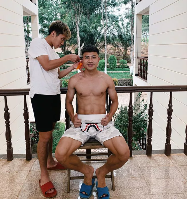 Giãn cách xã hội trong khuôn viên Hàm Rồng, Đinh Thanh Bình nhờ một đồng đội tại HAGL cắt tóc.