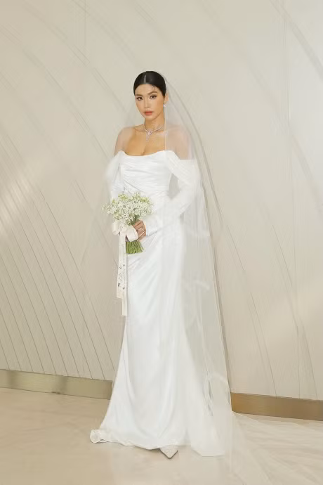 Bộ trang phục được Minh Tú chọn khi làm lễ là chiếc đầm trắng cúp ngực đơn giản với chất liệu cao cấp kèm theo chiếc lúp voan dài.