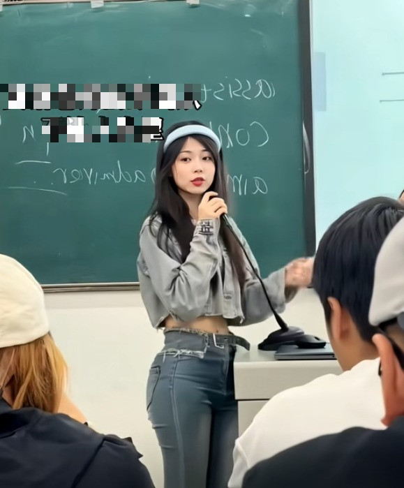 Trong video này, cô giáo ngoại ngữ đang đứng trong lớp học với vẻ ngoài xinh đẹp, thu hút mọi ánh nhìn.