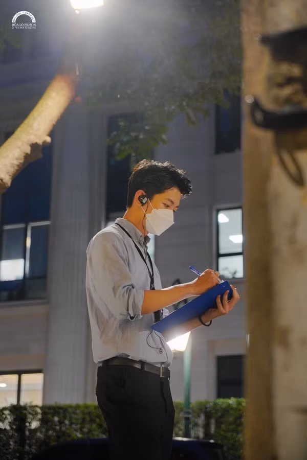 Trong ảnh, Thanh Tùng mặc áo sơmi đồng phục chỉn chu, đeo khẩu trang và bộ đàm, đang tập trung làm việc là đón khách tham quan tour đêm.