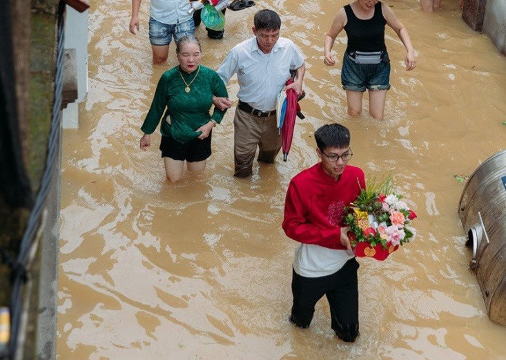 Chú rể sắn quần lội nước lụt vào đón dâu.