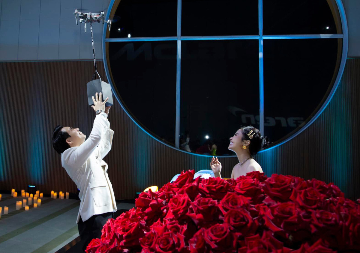 Mở đầu ngày kỉ niệm, đại gia Minh Nhựa chuẩn bị bó hoa hồng 300 bông đỏ tặng bà xã. Sau đó, doanh nhân 8X cho camera bay qua cửa sổ mang món quà đặc biệt anh dành tặng Mina Phạm.