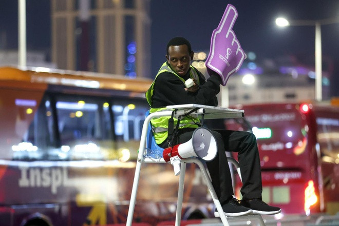 Ngồi trên chiếc ghế cao, cầm miếng xốp hình bàn tay chỉ đường và liên tục nói theo nhịp “Tàu điện ngầm? Hướng này”, Abubakr Abbass (23 tuổi, đến từ Kenya) hướng dẫn du khách tới Qatar xem World Cup 2022 hướng đi từ khu chợ lâu đời Souq Waqif đến ga gần nhất.