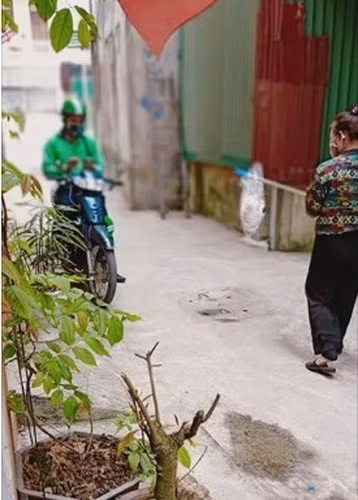 Người nhận hàng và chàng shipper giao tiền và hàng qua chiếc gậy và giữ đúng khoảng cách cần thiết theo khuyến cáo.