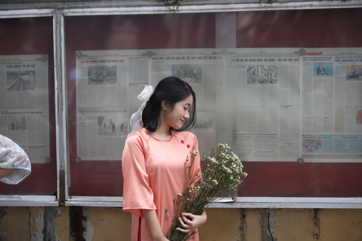 Vô vàn các nàng thơ tranh thủ diện áo dài, chụp ảnh trước bảng tin báo Hà Nội mới.