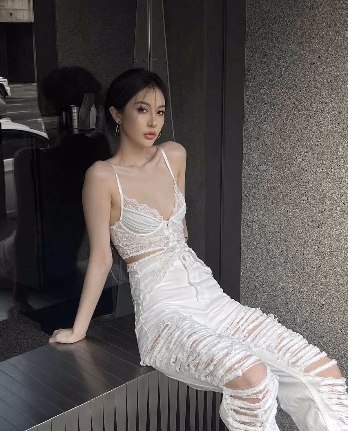 Người đẹp 10X mặc cả “cây trắng” với quần jeans cạp cao rách trải dọc thân, áo ren corset cúp ngực hớ hênh.