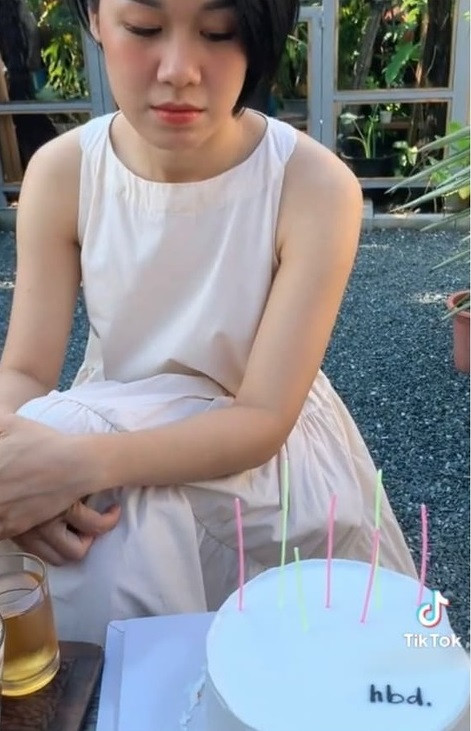 Ở đoạn clip còn lại, một cô gái trẻ trang điểm cẩn thận, mặc chiếc váy xinh xắn để mừng tuổi mới bên bạn bè. Tương tự tình huống trên, bạn nữ này cũng tỏ rõ sự háo hức và cố gắng duy trì động tác mở hộp nhẹ nhàng nhất có thể. Thế rồi, khi thấy chiếc bánh chỉ với vỏn vẹn 3 chữ “hbd” cùng vài chiếc nến cắm ở trên, cô nàng đã trưng ra biểu cảm thất vọng.