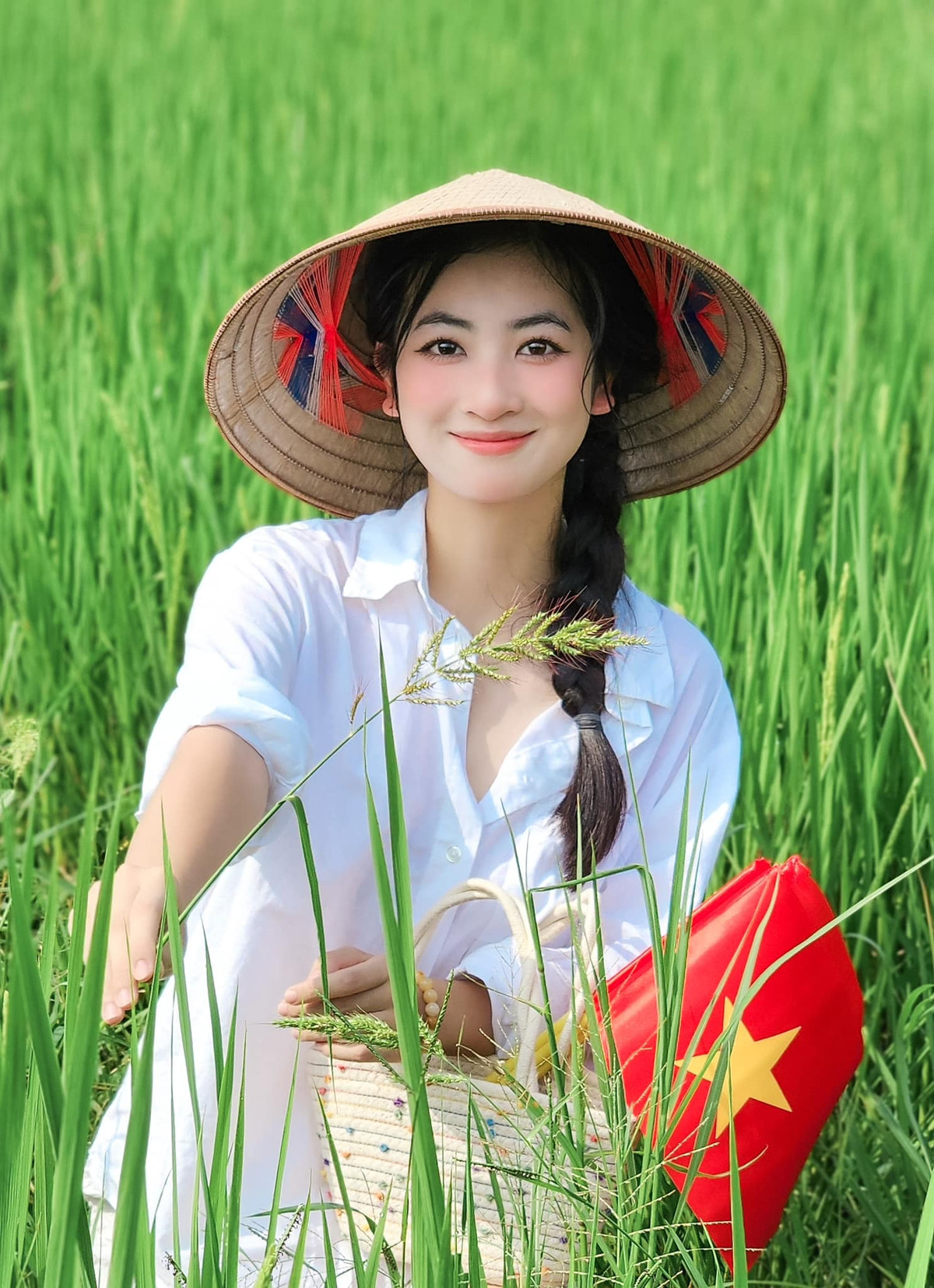 Hoa khôi Thái Nguyên Linh Chi thu hút với hình ảnh cầm cờ đứng giữa bạt ngàn lúa xanh. Nhan sắc 2K nổi bần bật.