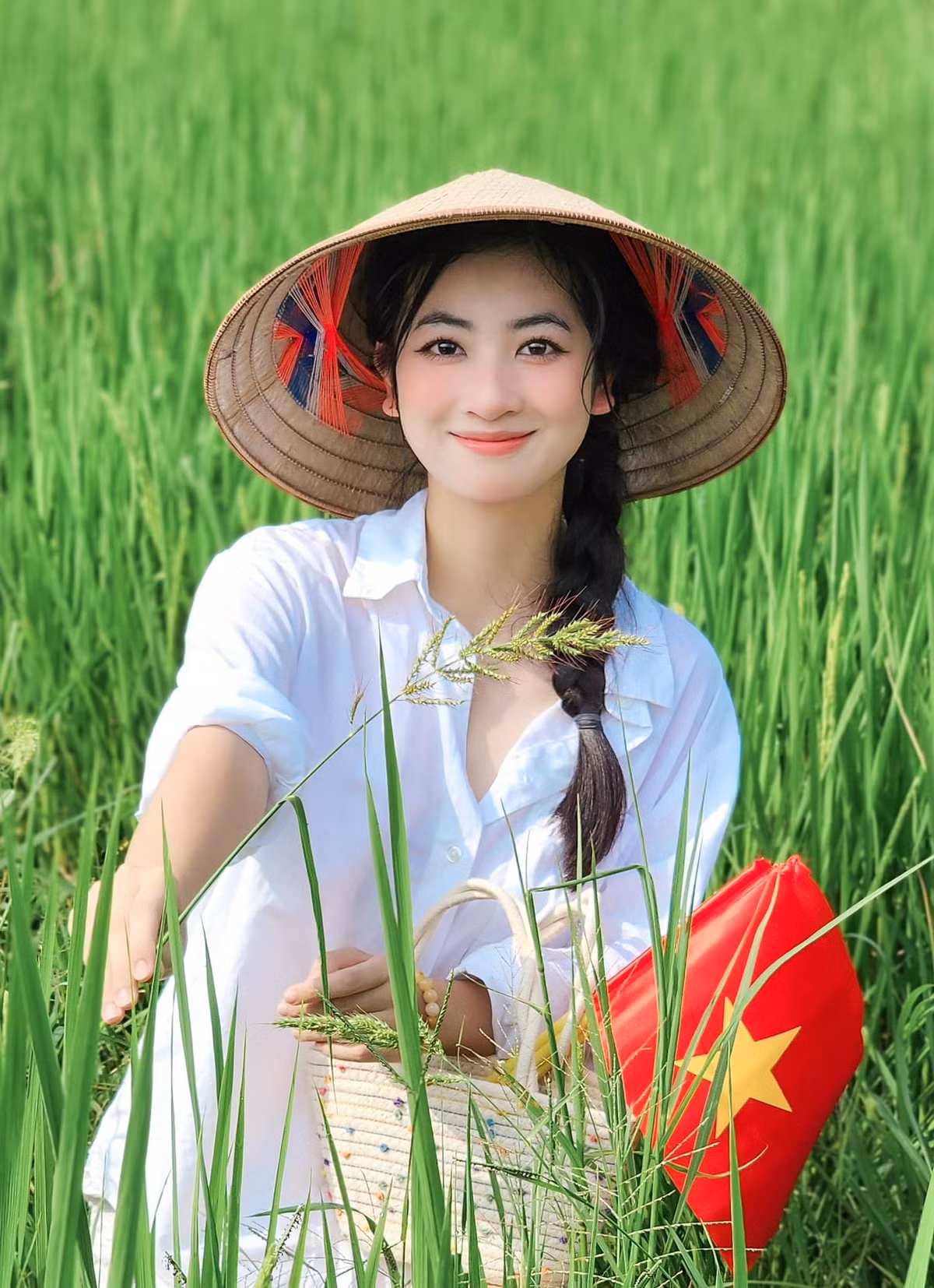 Hoa khôi Thái Nguyên Linh Chi thu hút với hình ảnh cầm cờ đứng giữa bạt ngàn lúa xanh. Nhan sắc 2K nổi bần bật.