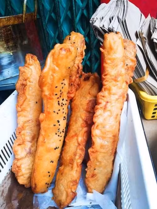 Mỗi chiếc bánh chuối chiên gồm nửa quả chuối được đập dập cho dẹt rồi phủ một lớp bột mì, chiên nhẹ rồi thả ra phủ một lớp bột mì khác, rắc một ít mè đen rồi chiên cho đến khi vàng giòn.