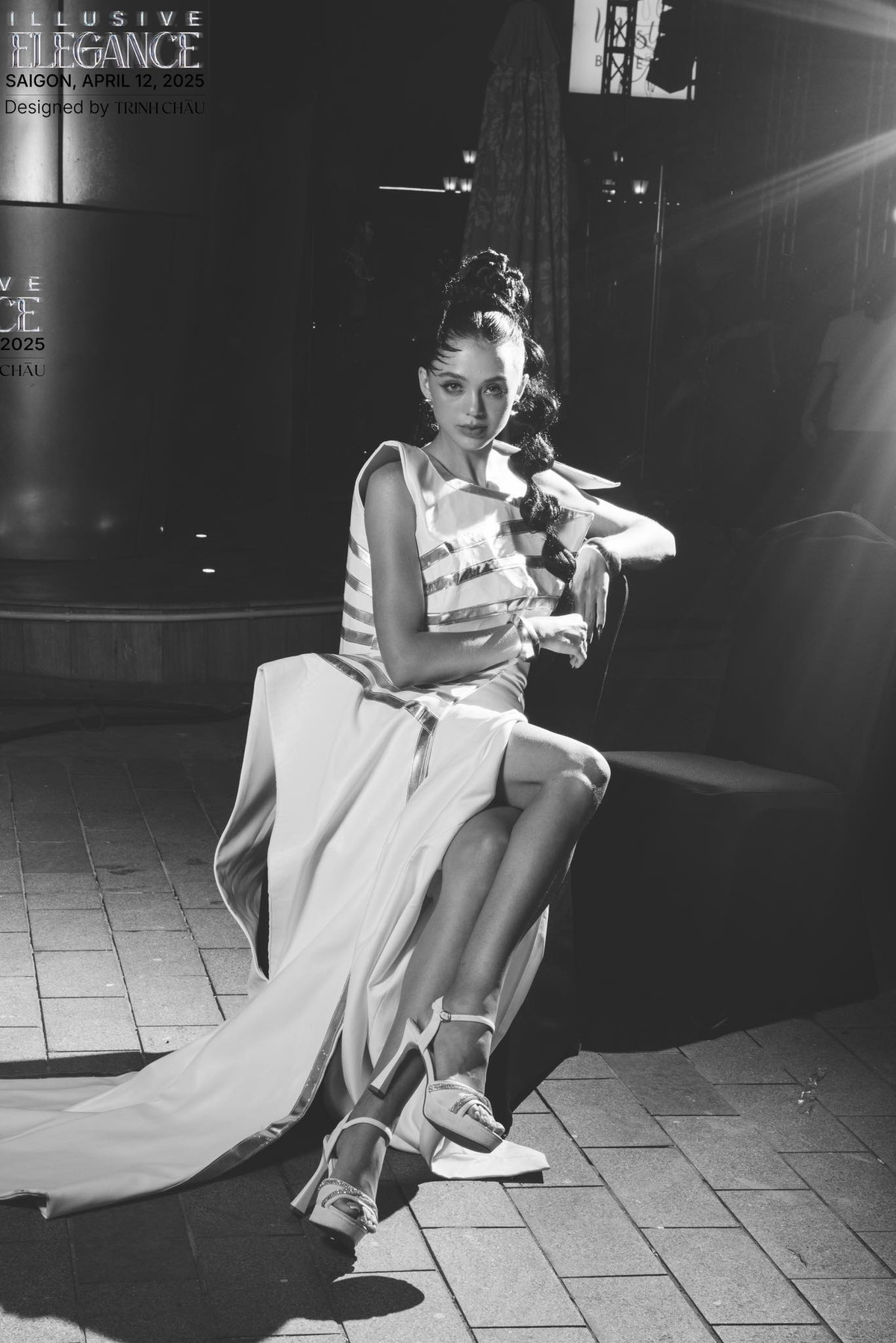 Dianka mặc một chiếc váy dài, thiết kế độc đáo với phần thân trên có các đường cắt xẻ và họa tiết sọc ngang, tôn lên vóc dáng thanh mảnh. Phần váy dưới xòe rộng, kéo dài xuống đất, tạo vẻ kiêu sa.