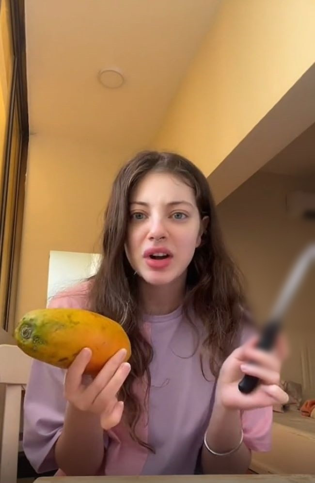 Tương tự, trước đó một cô gái nước ngoài cũng có màn "làm quen" vô cùng cồng kềnh với quả đu đủ.
