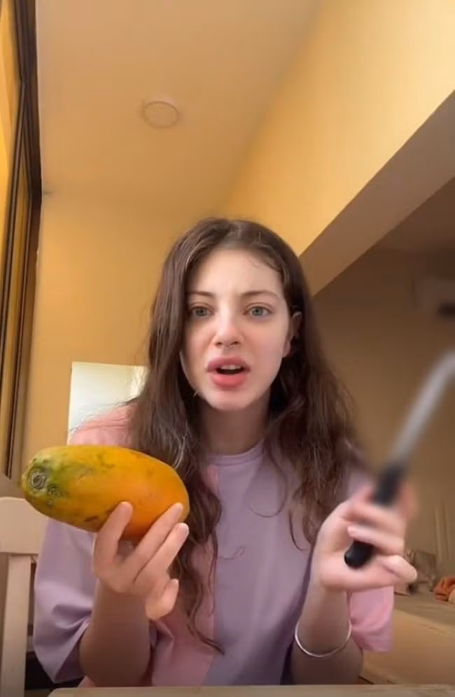 Tương tự, trước đó một cô gái nước ngoài cũng có màn "làm quen" vô cùng cồng kềnh với quả đu đủ.