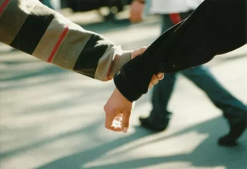 Một cặp đôi nam - nữ trẻ tuổi đang cùng nhau ngồi trên vỉa hè, ngắm nhìn phố xá tấp nập đông đúc người qua lại.