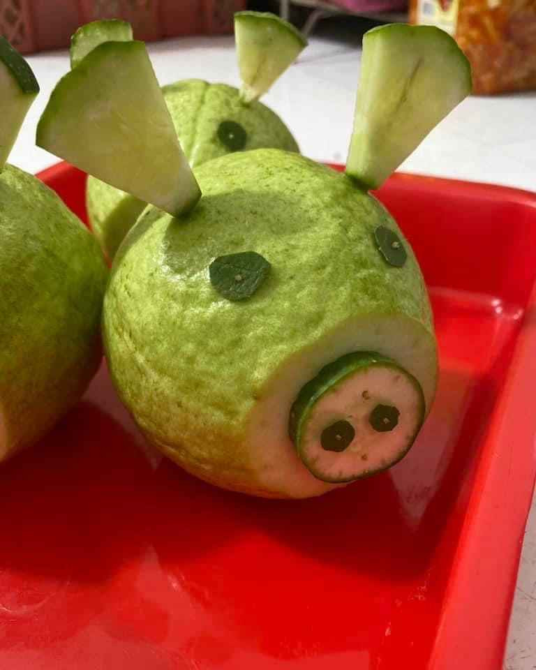 Lần đầu tiên được giao trọng trách làm mâm cỗ cho con mang đi học nhưng có vẻ hơi nhìn chú lợn làm từ quả ổi này có vẻ hơi bất ổn...