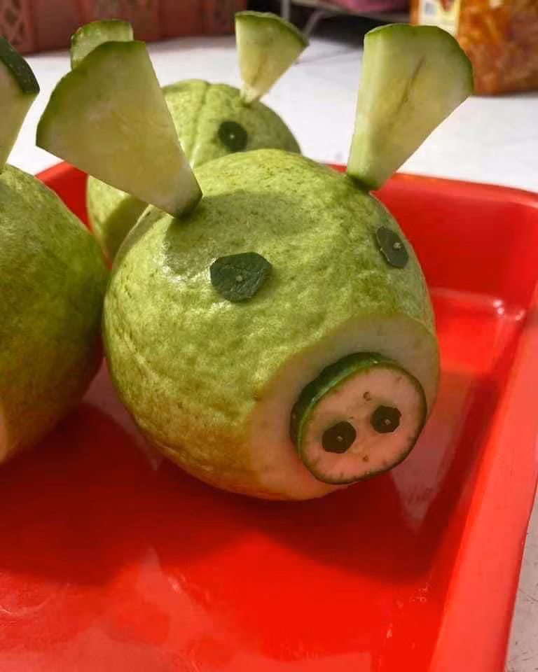 Lần đầu tiên được giao trọng trách làm mâm cỗ cho con mang đi học nhưng có vẻ hơi nhìn chú lợn làm từ quả ổi này có vẻ hơi bất ổn...