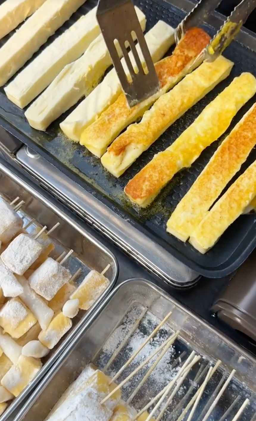 Nguyên liệu chính là thanh phô mai dài khoảng 30cm, được áp chảo trong vài phút cho đến khi lớp ngoài vàng ươm, giòn nhẹ. Để tăng thêm độ hấp dẫn, người chế biến sẽ rưới một lớp sữa đặc lên trên ngay khi phô mai còn nóng, tạo nên sự kết hợp hoàn hảo giữa vị ngọt dịu và độ béo đậm đà.