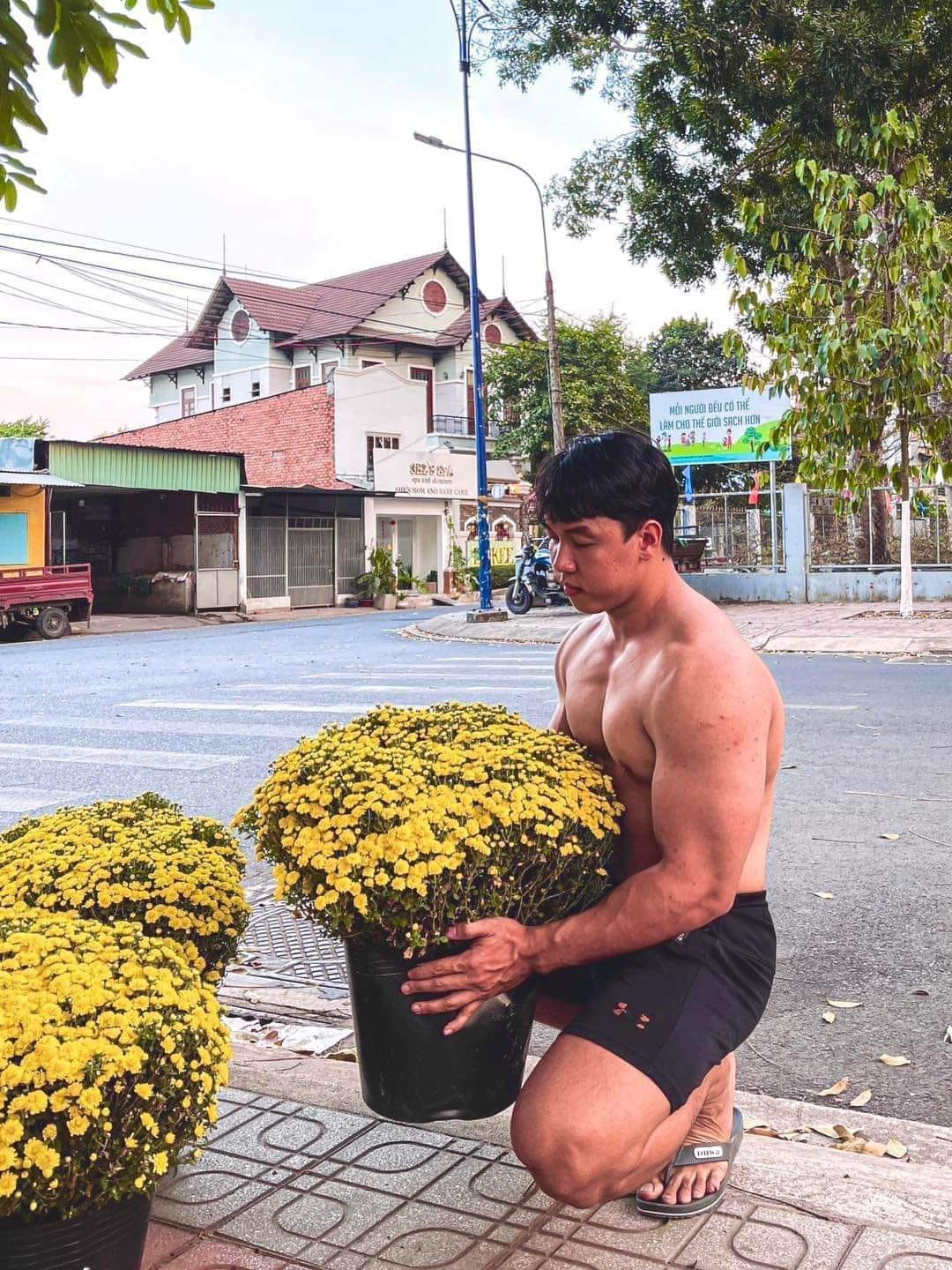 Trong ảnh cặp đôi nam chính chỉ mặc chiếc quần đùi, để lộ cơ bắp cuồn cuộn với thân hình 6 múi chuẩn chỉnh cạnh tấm biển: “Tết phải có cúc mâm xôi”.