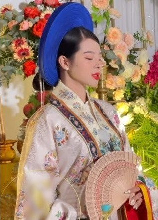 Vừa xuất hiện, cô dâu đã chiếm trọn ánh nhìn với chiếc áo tone trắng, đầu đội mấn xanh. Toàn bộ thân áo được trang trí bằng hoa văn dạng hình tròn khép kín, đan xen là những hình phượng múa cùng hoa lá đính thêm kim tuyến lấp la lấp lánh.