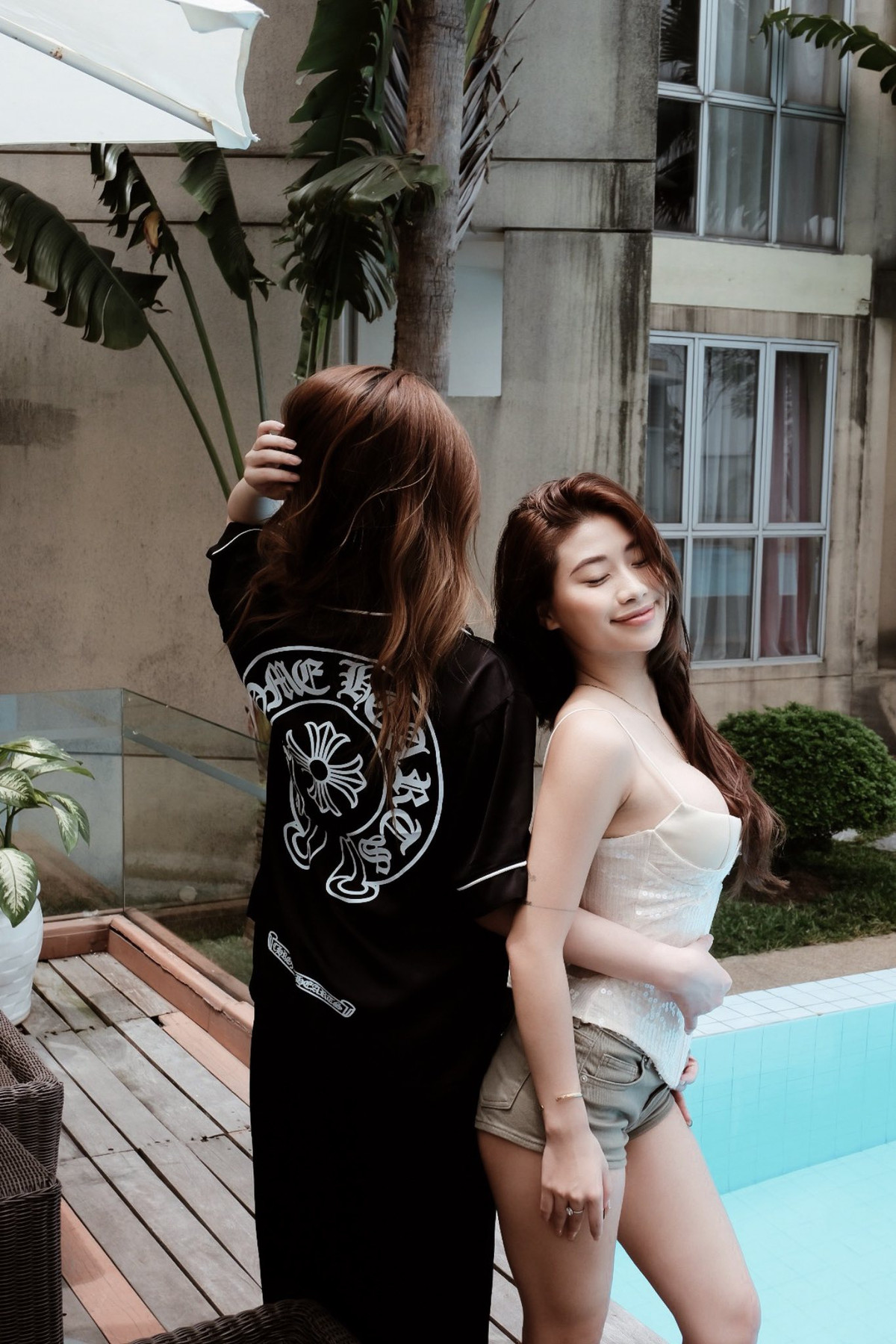 Chiếc áo tắm với phần áo có nút thắt phía trước tôn lên vòng một đầy đặn. Mái tóc dài màu nâu sẫm, để xõa tự nhiên, bay nhẹ trong gió, tạo cảm giác năng động.
