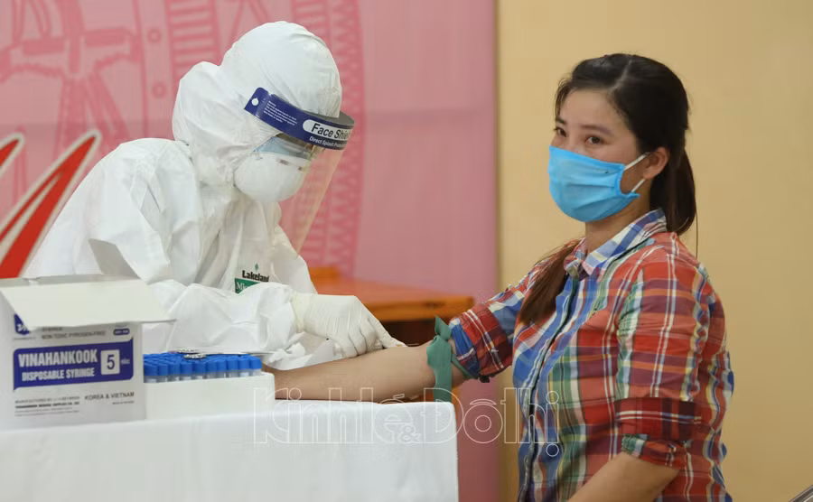Người lao động tự do tại chợ Long Biên được cán bộ y tế lấy mẫu máu để xét nghiệm nhanh COVID-19.