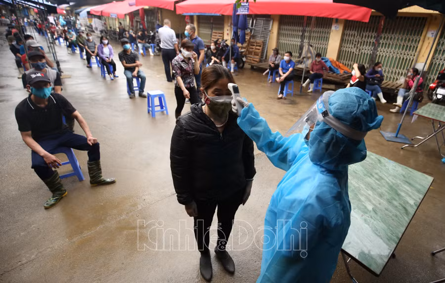 Cán bộ y tế đo thân nhiệt cho người dân trước khi vào làm xét nghiệm.