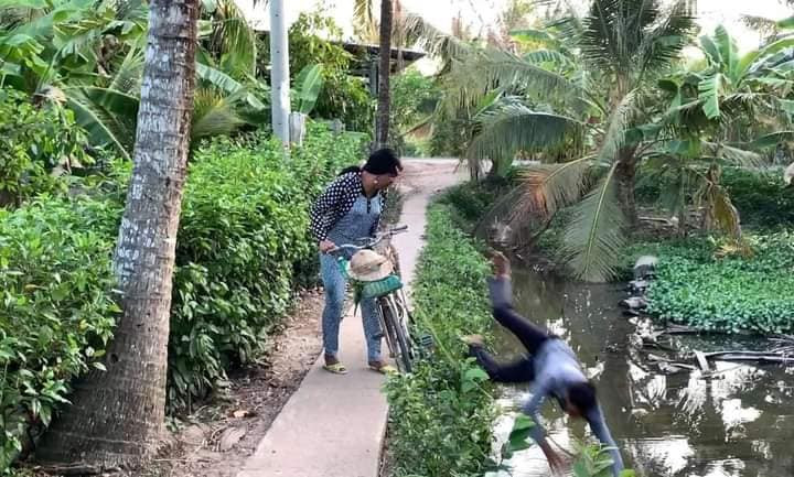 Sau khi đi qua một đoạn đường dài, đến bờ kênh thì anh chồng ngã nhào xuống. Cô vợ liền gọi mẹ chồng ra chứng kiến.