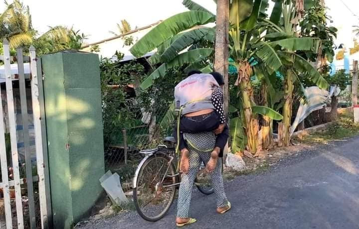 Trong ảnh, người chồng say xỉn đến nổi không đứng vững nên cô vợ phải lấy dây cột lại, để nằm lên yên xe rồi một tay ôm người, một tay dắt xe đi.