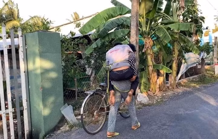 Trong ảnh, người chồng say xỉn đến nổi không đứng vững nên cô vợ phải lấy dây cột lại, để nằm lên yên xe rồi một tay ôm người, một tay dắt xe đi.