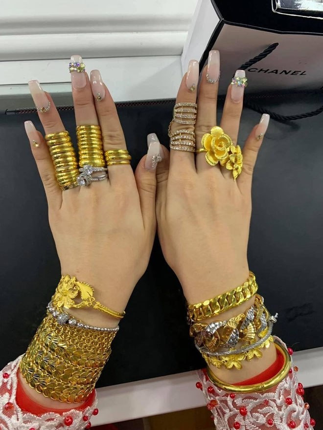 Đếm sơ sơ cô dâu đeo đầy vàng sở hữu 11 chiếc vòng vàng bản to ở hai cổ tay, 27 chiếc nhân tròn trơn cùng 2 nhẫn kim cương tại các ngón tay và 5 kiềng vàng ở cổ. Ước tính tổng giá trị của hồi môn lên đến cả tỷ đồng.