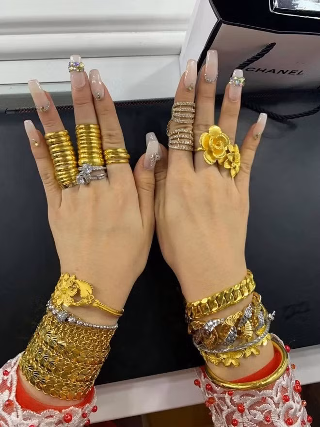 Đếm sơ sơ cô dâu đeo đầy vàng sở hữu 11 chiếc vòng vàng bản to ở hai cổ tay, 27 chiếc nhân tròn trơn cùng 2 nhẫn kim cương tại các ngón tay và 5 kiềng vàng ở cổ. Ước tính tổng giá trị của hồi môn lên đến cả tỷ đồng.