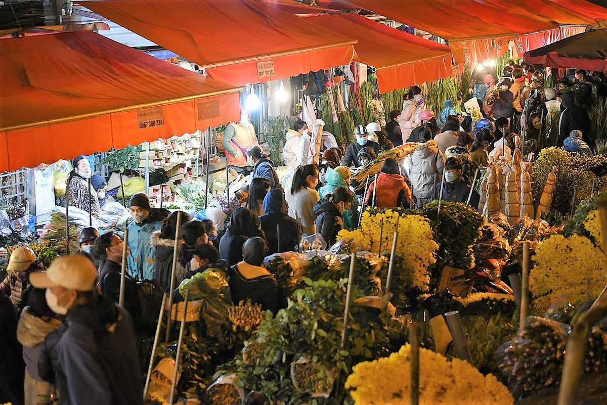 Nhiều người mặc áo mưa, bất chấp thời tiết mưa lạnh để đi chợ mua hoa.