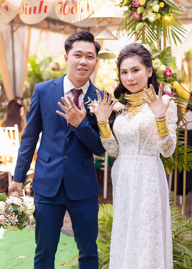 Trên cổ cô dâu là hàng chục chiếc kiềng vàng lấp lánh chồng chất lên nhau, hai bên cổ tay được che kín với những chiếc lắc vàng.
