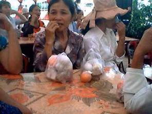 Theo đó, trong khi người đàn ông ngồi cùng mâm cỗ vẫn đang ăn uống bình thường thì người phụ nữ này lại gắp hết thức ăn trên đĩa vào túi nilon. Dù chiếc túi đựng khá đầy nhưng người này vẫn nhiệt tình gắp, mặc cho người đối diện vẫn đang thưởng thức cỗ cưới.