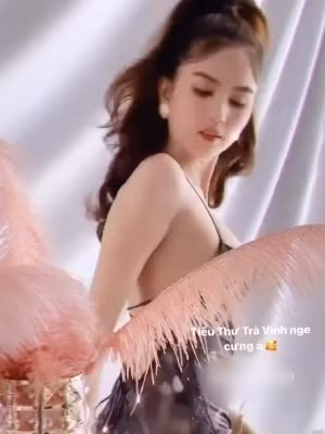 Ngọc Trinh ngồi hẳn lên bàn với nhiều phụ kiện trang trí như ly, đĩa, giày dép,...