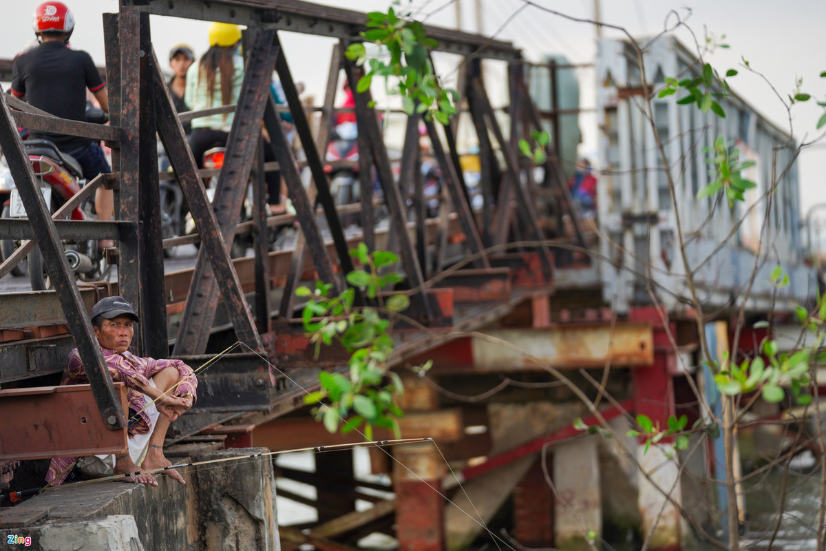 Cầu sắt đã quá cũ, người dân dễ dàng trèo qua hàng rào để ngồi câu cá trên mố cầu.