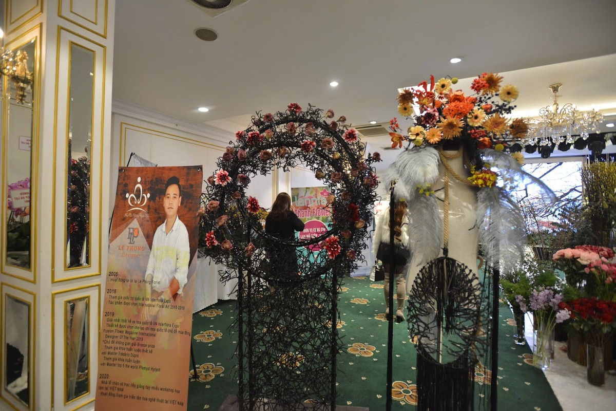 Tác phẩm chiến binh hoa của nhà thiết kế Lê Phong, sử dụng các loại hoa màu cam, đất và nâu trầm cùng lông vũ để thể hiện sự mềm mại nhưng cũng cực kỳ mạnh mẽ, lạnh lùng nhưng cũng rất nồng ấm của các chiến binh ngoài mặt trận.