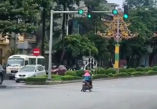 Theo đó, clip quay tại một ngã tư đường, hai bên các phương tiện đều đang đợi đèn đỏ. Trong khi mọi người nghiêm túc chấp hành thì xuất hiện một người phụ nữ đi xe máy, mặc mũ áo kín mít dừng xe giữa đường.