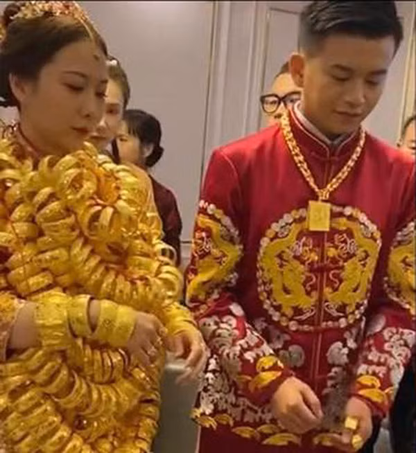 Cặp vợ chồng trẻ diện trang phục cưới truyền thống màu đỏ vô cùng lộng lẫy, nổi bật. Điều khiến dân mạng chú ý chính là những chiếc vòng vàng được nối lại đeo trên người cô dâu.