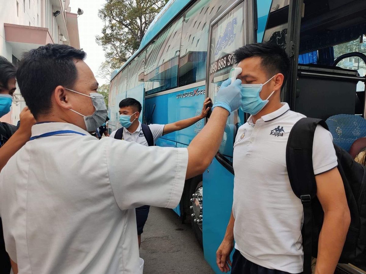 Các cầu thủ Hà Nội FC bước xuống khỏi xe buýt và ngay lập tức được đo thân nhiệt.