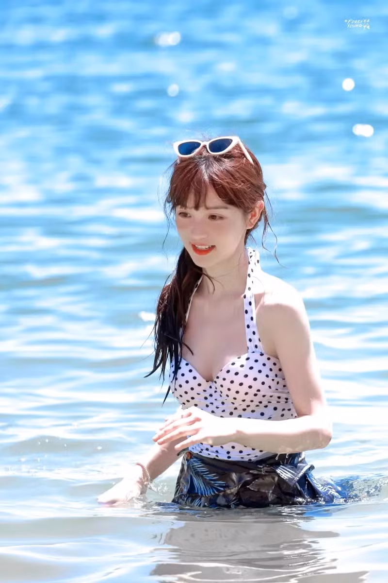 Trong hình, nữ diễn viên sinh năm 1997 diện thiết kế đồ bơi liền mảnh cổ yếm, hoạt tiết chấm bi, cô quấn thêm một lớp khăn dày bên dưới, tạo thành váy nhằm tiết chế sự gợi cảm.
