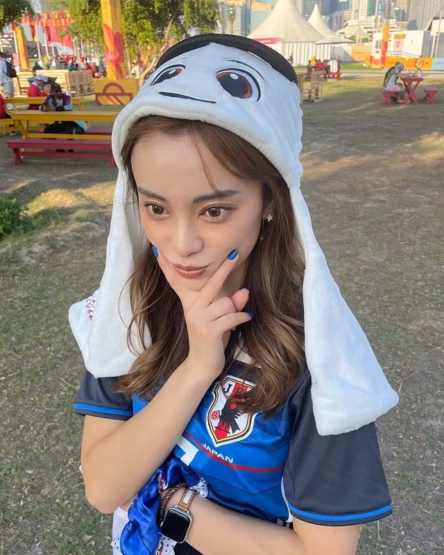 Shono xuất hiện tại SVĐ Khalifa International Stadium hôm 23/11 trong trang phục quần jeans, áo đấu của đội nhà và cầm theo quốc kỳ Nhật Bản.