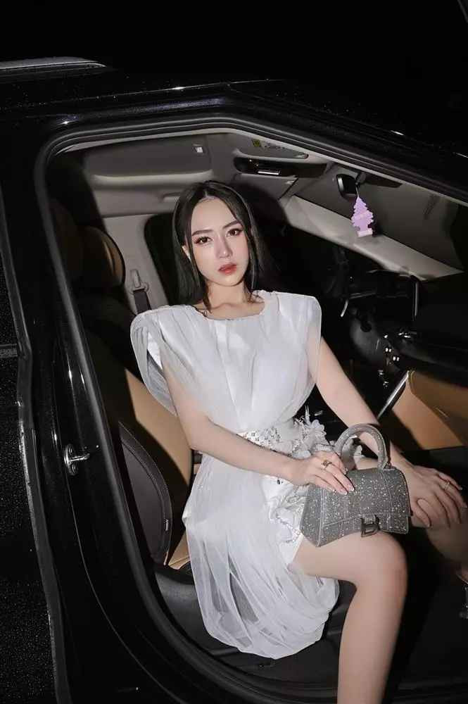 Trong ảnh, con gái đại gia Minh Nhựa diện chiếc váy trắng sang chảnh, xách túi hiệu, làm tóc và make-up kỹ lưỡng.