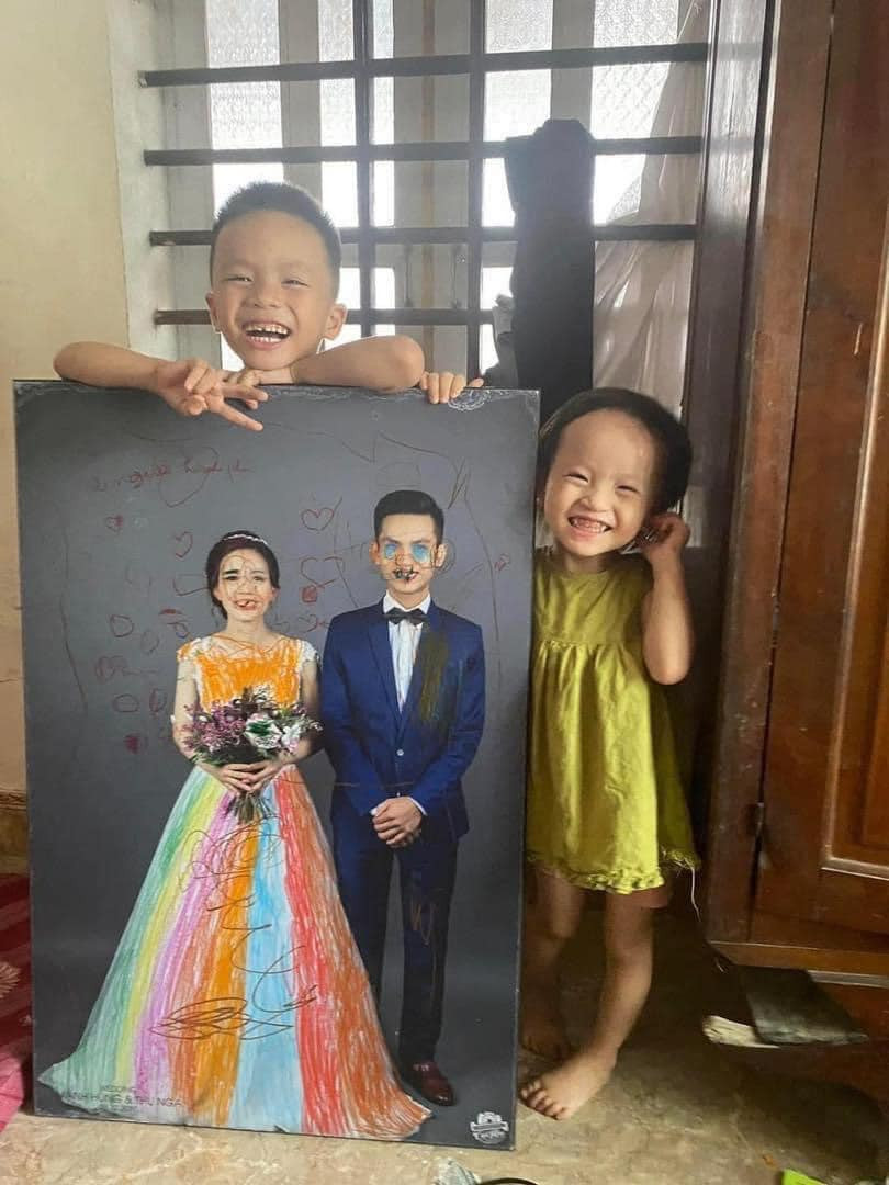 Cụ thể, tấm ảnh cưới của cặp vợ chồng trẻ đã được các con đem ra tô màu với những đường nét nghệch ngoạc và khi bắt được "thủ phạm", cả 2 cùng đứng chụp ảnh với tác phẩm.